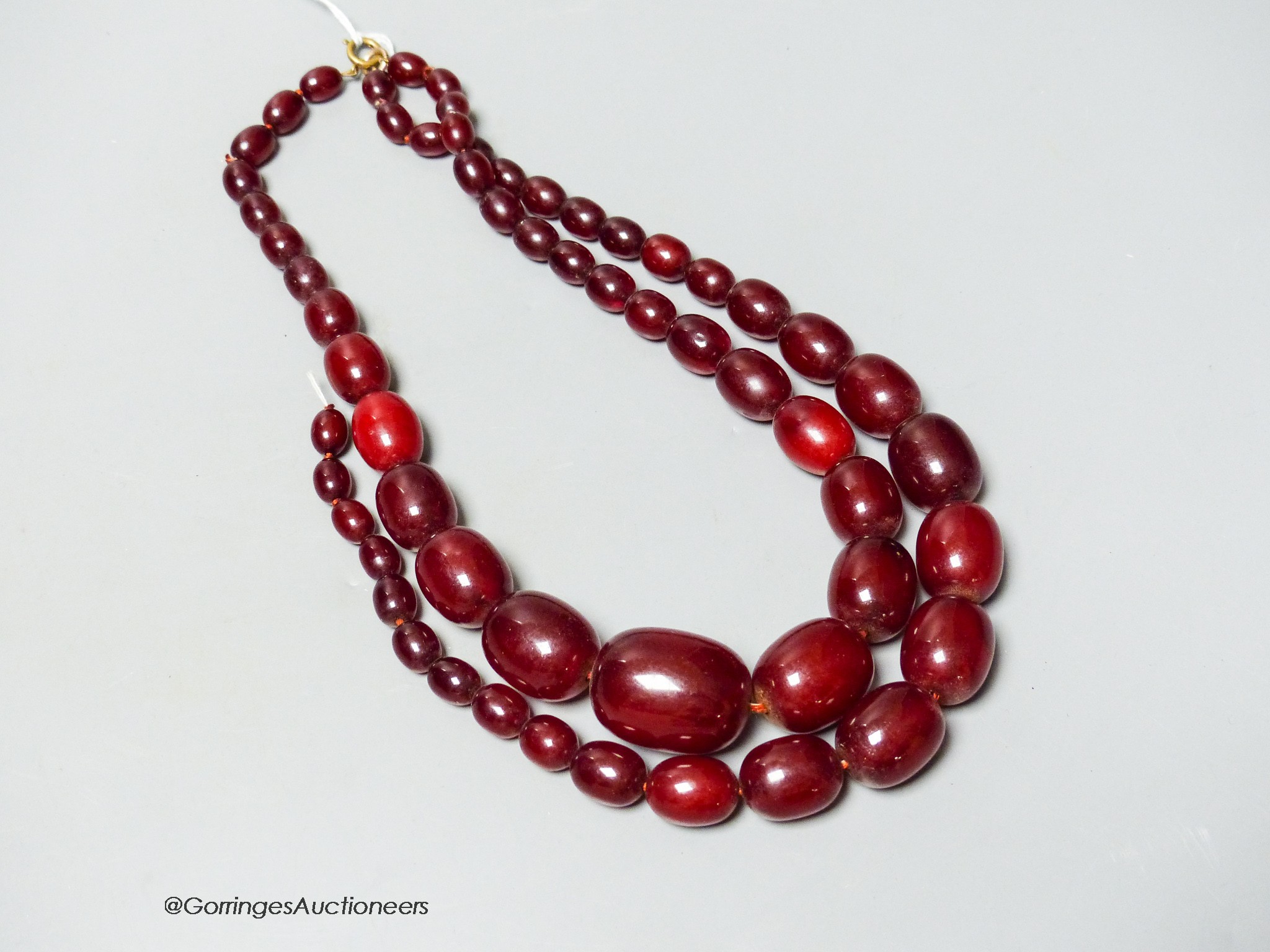 A double strand simulated oval cherry amber bead choker necklace (string broken), 44cm, gross weight 102 grams.